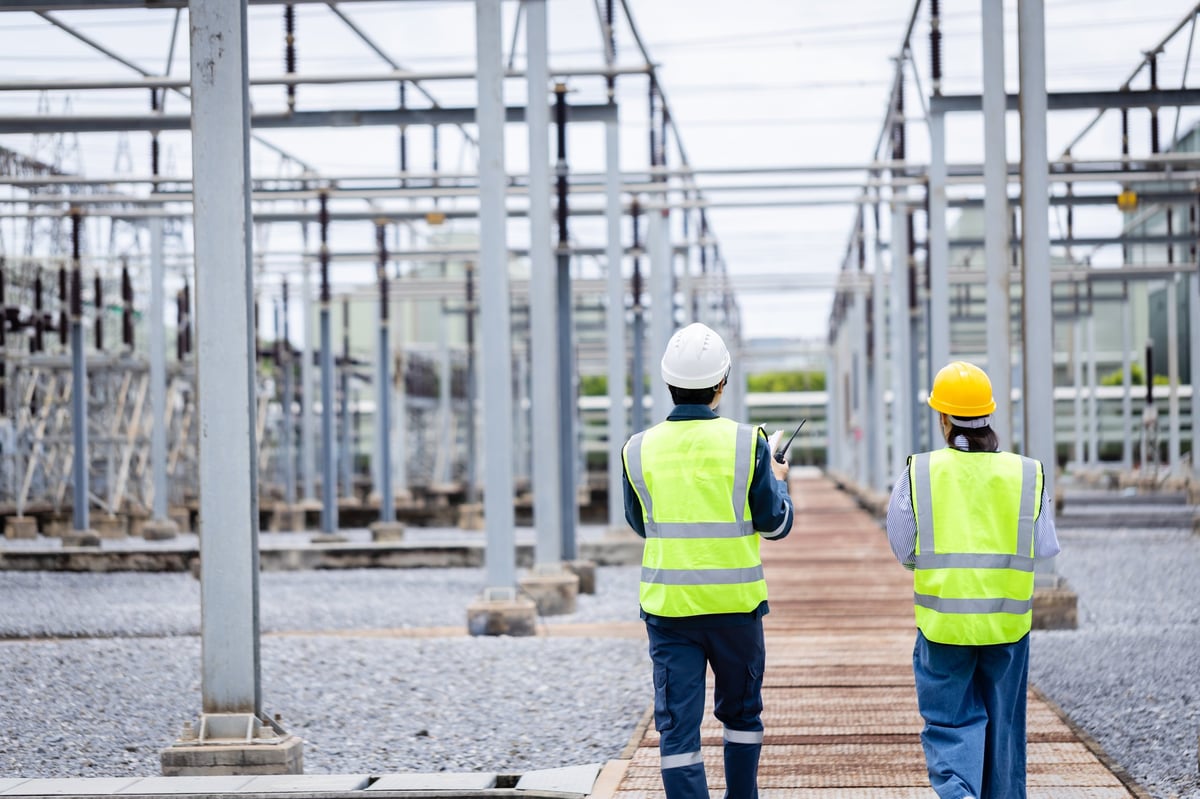 Engineer inspecting high voltage equipment at a power substation