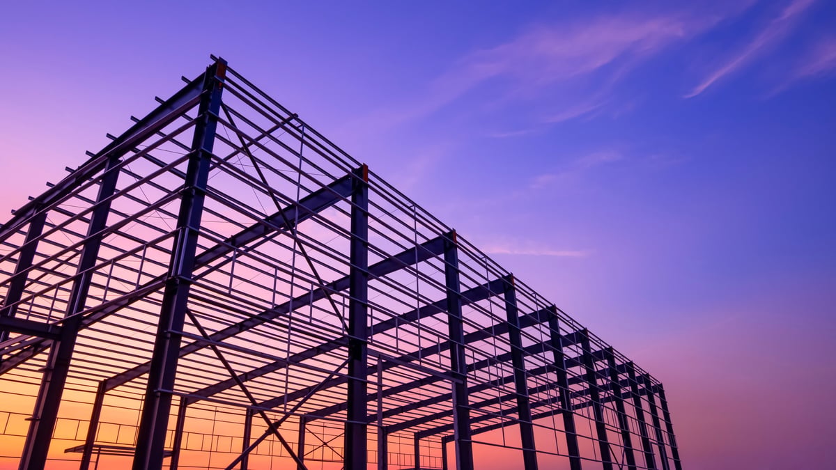Steel framework of an industrial building under construction against an evening sky